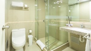 Une salle de bain moderne avec une douche à parois de verre, des toilettes et un meuble-lavabo avec des articles de toilette.