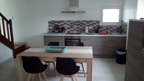 A modern kitchen with a wooden table and chairs, a built-in oven, and a window above the sink. - House in the countryside 10 minutes from beautiful sandy beaches, ideal for visits (cast)