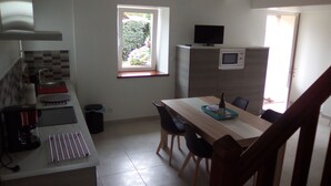 A compact kitchen with a dining table, chairs, a microwave, and a TV. - House in the countryside 10 minutes from beautiful sandy beaches, ideal for visits (cast)