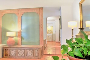 A reception area with a wooden desk, two lamps, a mirror, and a potted plant.