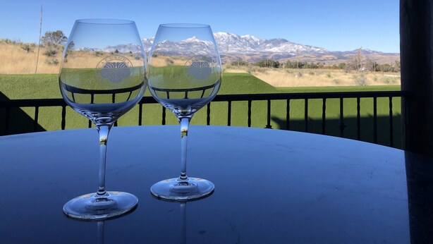 Dos copas de vino vacías sobre una mesa con vistas a un paisaje montañoso.