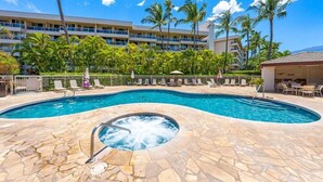 A swimming pool with a hot tub, surrounded by palm trees and lounge chairs, with a hotel building in the background. - Remodeled 2BD Condo Across Beach Pool AC - Maui Banyan P301 (Kihei)