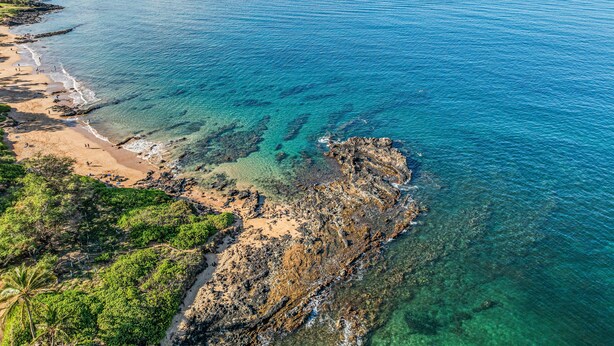 A coastal landscape with clear blue waters, a sandy beach, and rocky outcrops. - Remodeled 2BD Condo Across Beach Pool AC - Maui Banyan P301 (Kihei)