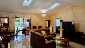 A living room with a sofa, a coffee table, a TV, and a piano. - Spacious property in a quiet neighborhood, 30% discount for stays over 28 days (Lake Worth)