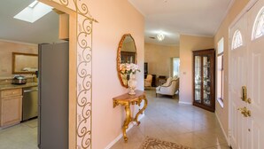 A spacious living area with a large mirror, a decorative console table, and a modern kitchen in the background. - Spacious property in a quiet neighborhood, 30% discount for stays over 28 days (Lake Worth)