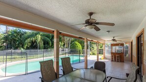 A covered outdoor area with a glass table and chairs, a pool, and a bar area. - Spacious property in a quiet neighborhood, 30% discount for stays over 28 days (Lake Worth)