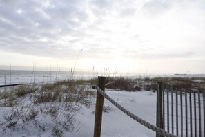 A sandy beach with a wooden fence and rope barrier.