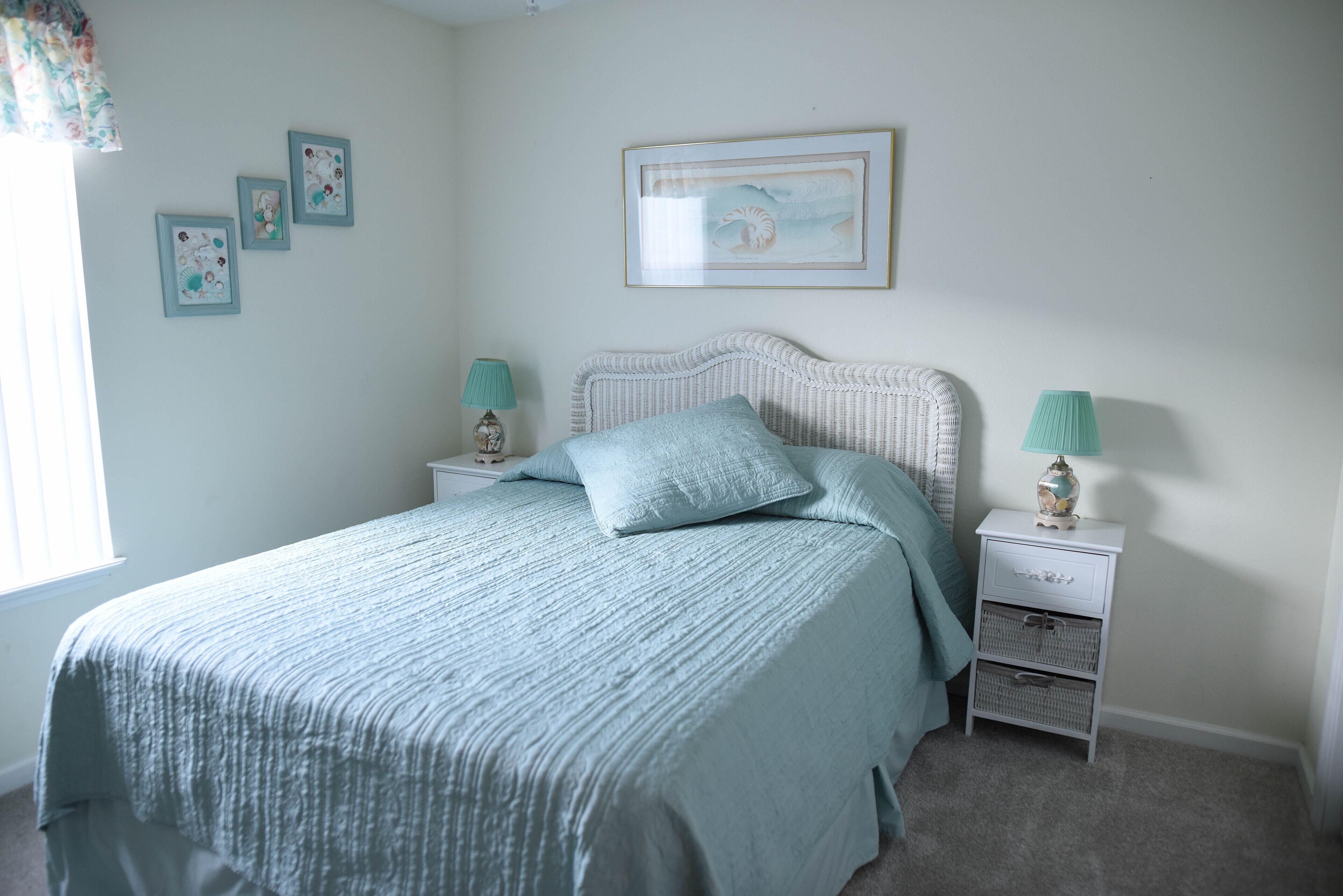 Une chambre à coucher avec un lit, deux tables de chevet, une lampe et des œuvres d’art murales.