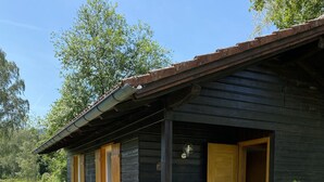 Eine Holzhütte mit Veranda, Bank und Tür.