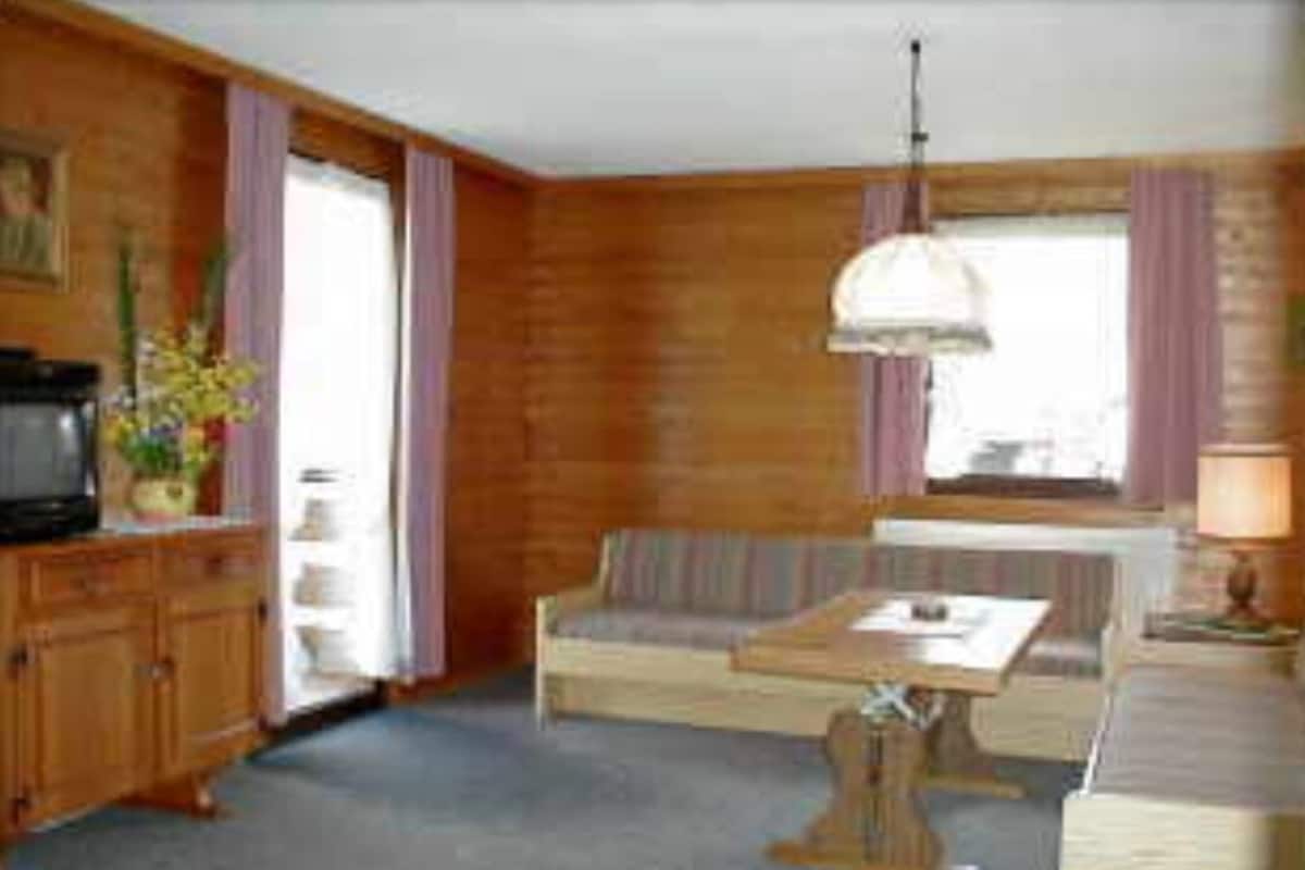 A room with wooden walls, a sofa, a table, and a television.
