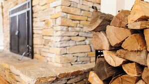 A stone fireplace with a stack of firewood beside it. - The Stone House Between the Streams (Gap)
