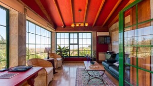 Une pièce spacieuse avec de grandes fenêtres, un plafond rouge et un coin salon confortable avec un canapé et des fauteuils.