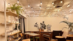A cozy cafe with wooden furniture, hanging light bulbs, and potted plants. - Pop Up Hotel Krone Zürich (Zürich)