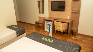 A hotel room with two beds, a desk, a chair, a television, and a small refrigerator. - VOA Hotel Caxambu (Caxambu)
