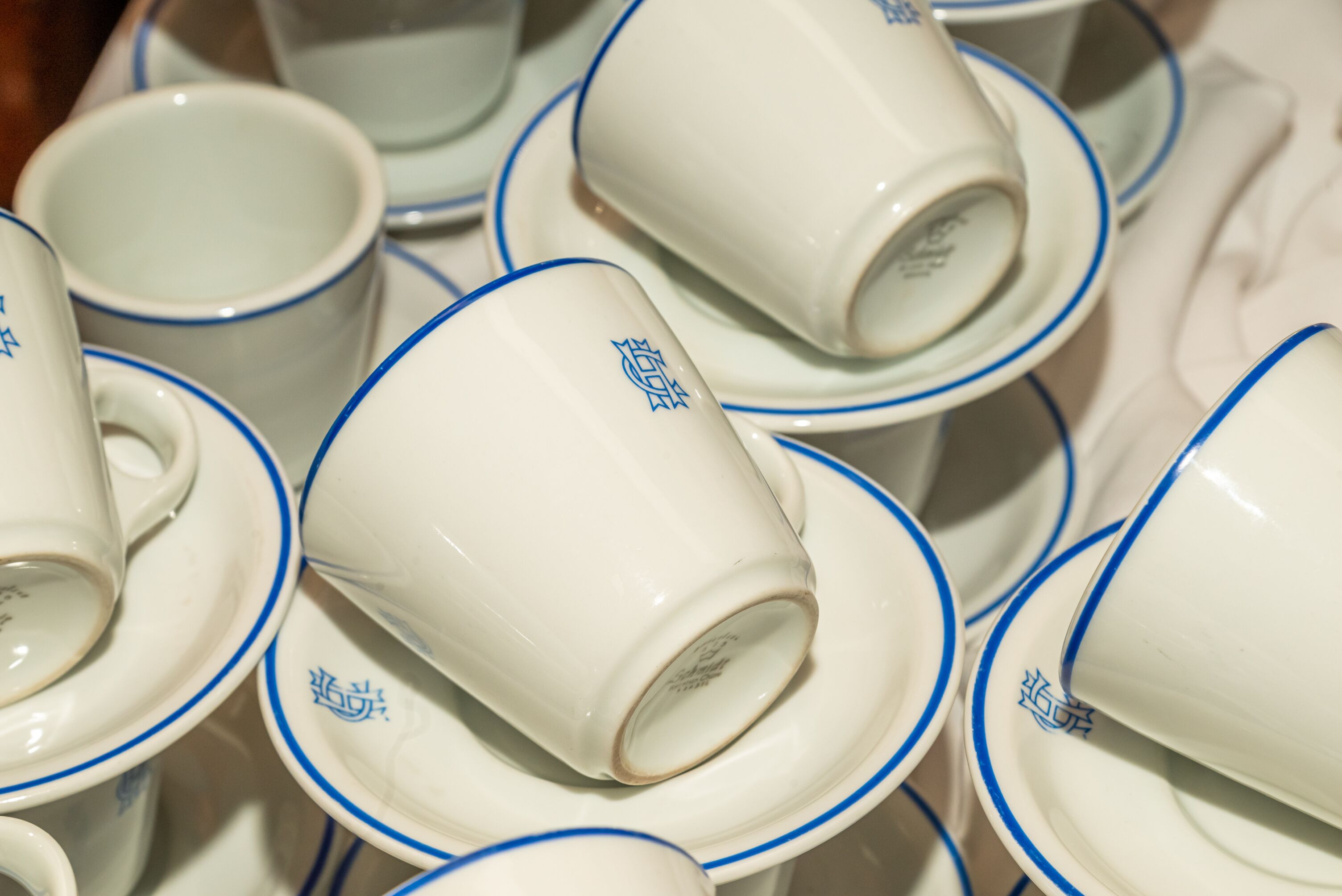 A collection of white cups with blue rims and a blue logo, arranged closely together.