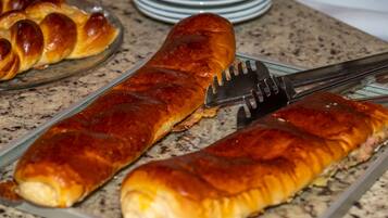 Uma salsicha assada e comprida sobre um prato de vidro.