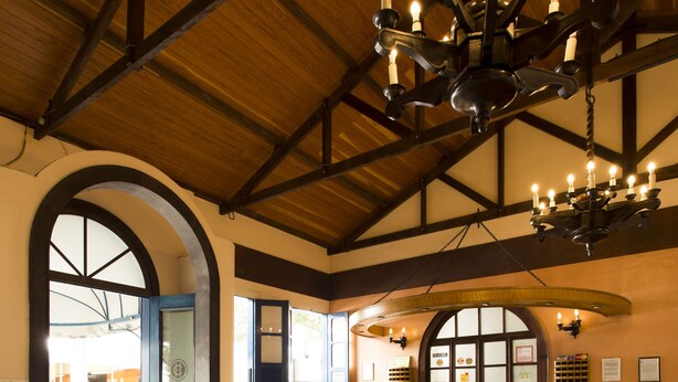 A spacious lobby with a large circular emblem on the floor, a reception desk, and a chandelier. - VOA Hotel Caxambu (Caxambu)