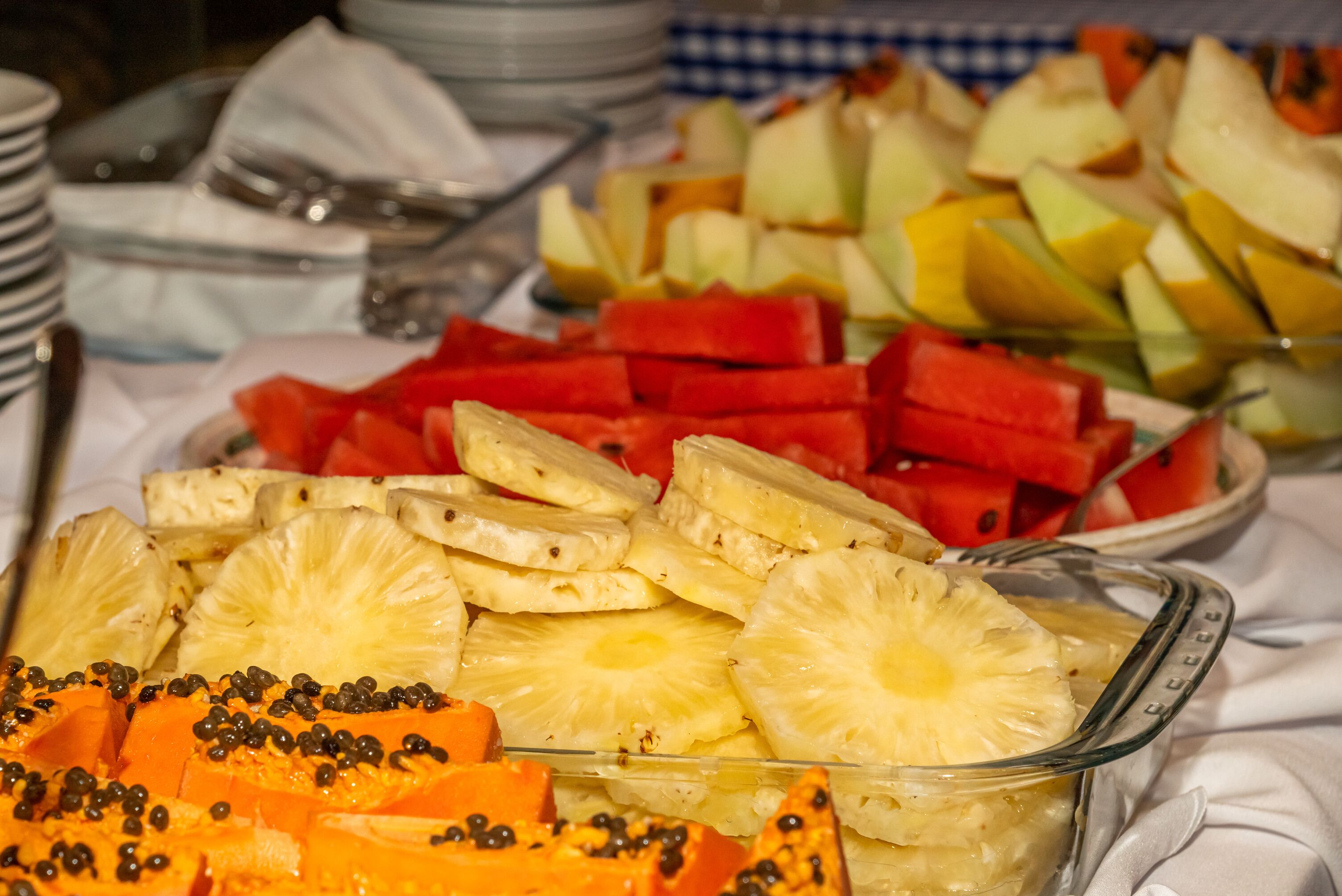 Un buffet proposant une variété de fruits, notamment de l’ananas, de la pastèque et de la papaye.