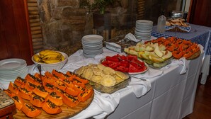 A buffet table with various fruits and vegetables, including sliced papaya and pineapple, arranged on a white tablecloth. - VOA Hotel Caxambu (Caxambu)