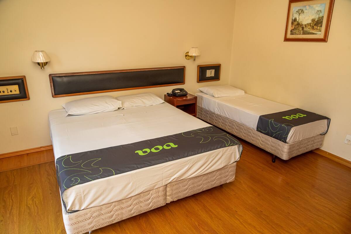 A hotel room with two beds, each with a 'boa' branded bedspread, a bedside table with a phone, and wall-mounted lamps.