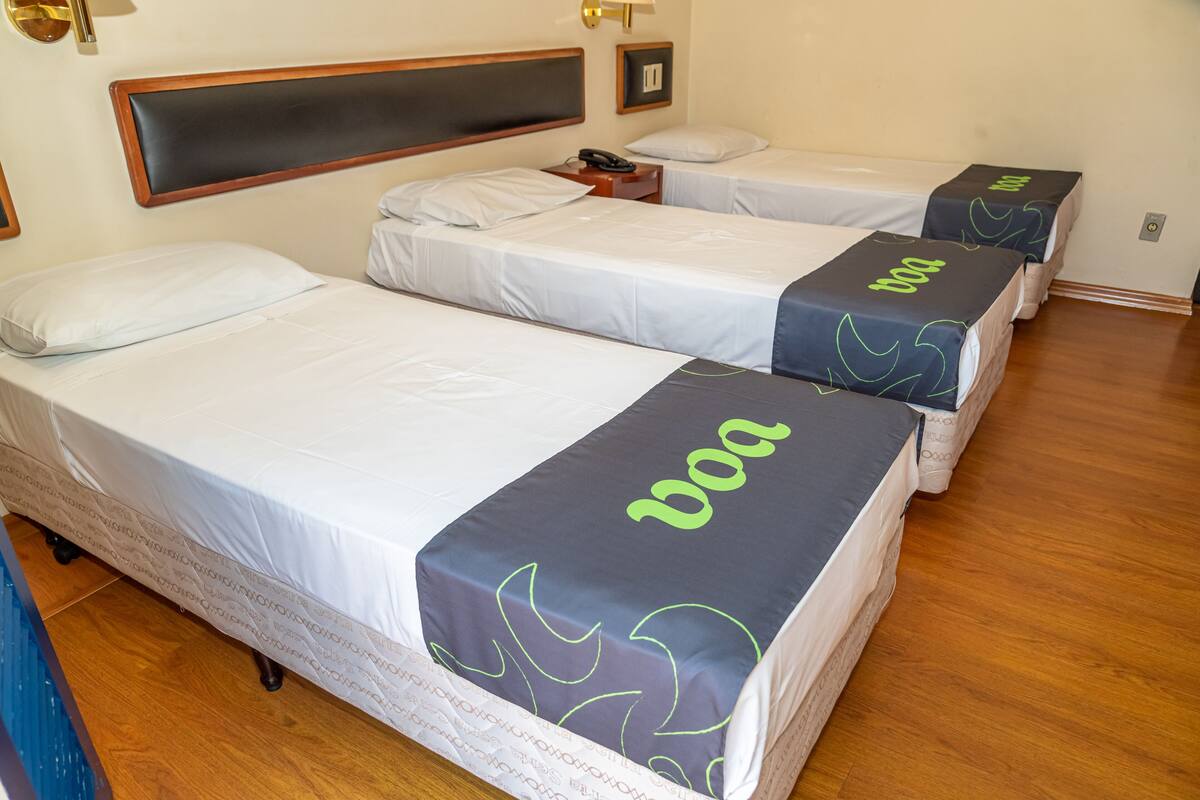 A hotel room with two single beds, each with a 'boa' branded bedspread.