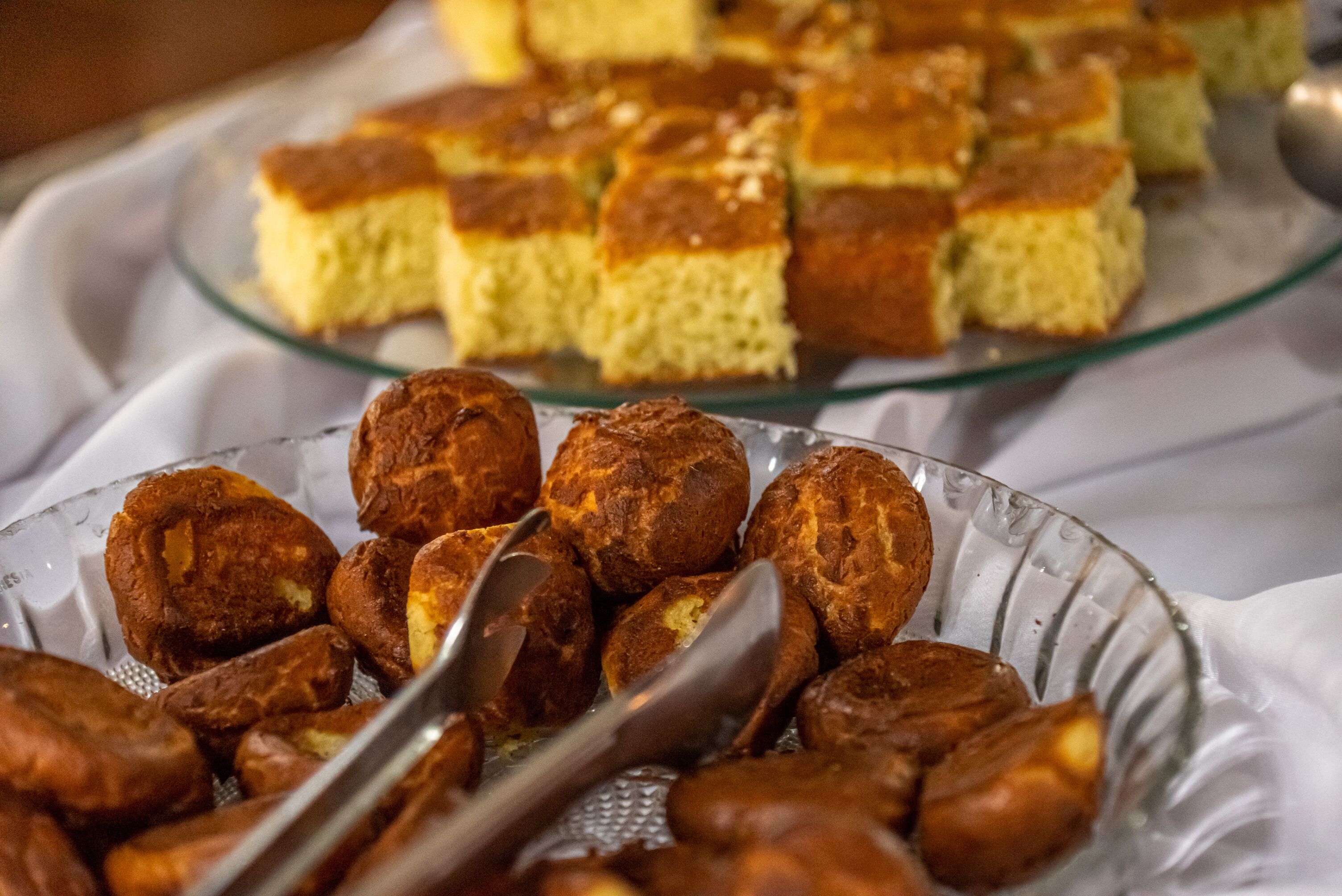 Un plat en verre contenant des pâtisseries rondes et un autre plat en verre contenant des pâtisseries carrées.