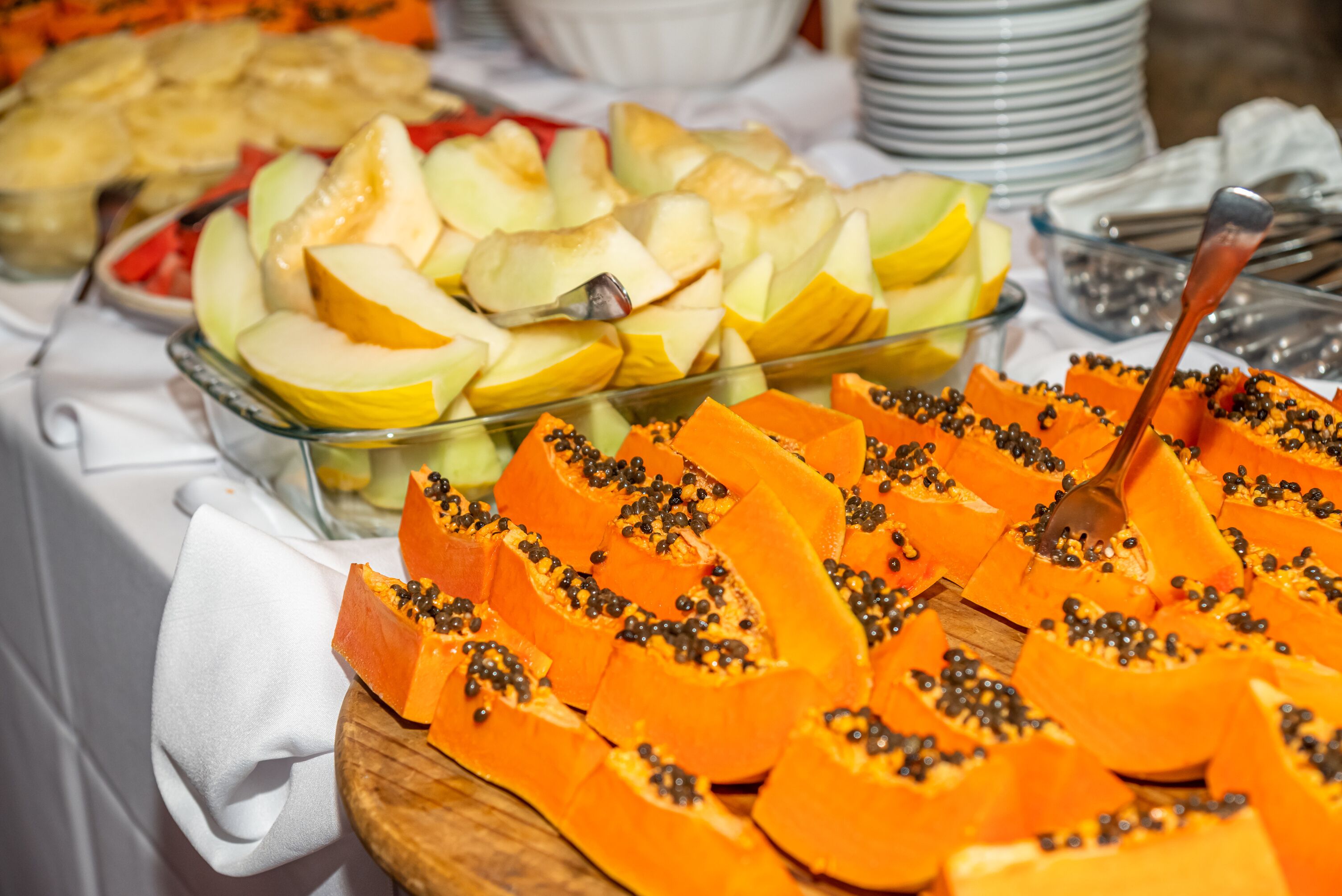 Una mesa de buffet con frutas cortadas, como manzanas y papaya.