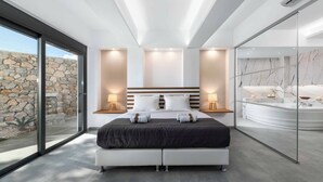 A modern bedroom with a large bed, a glass shower enclosure, and a stone wall outside.