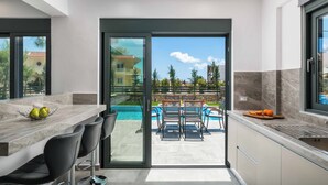 A modern kitchen with a large island, bar stools, and a view of a pool and outdoor seating area.