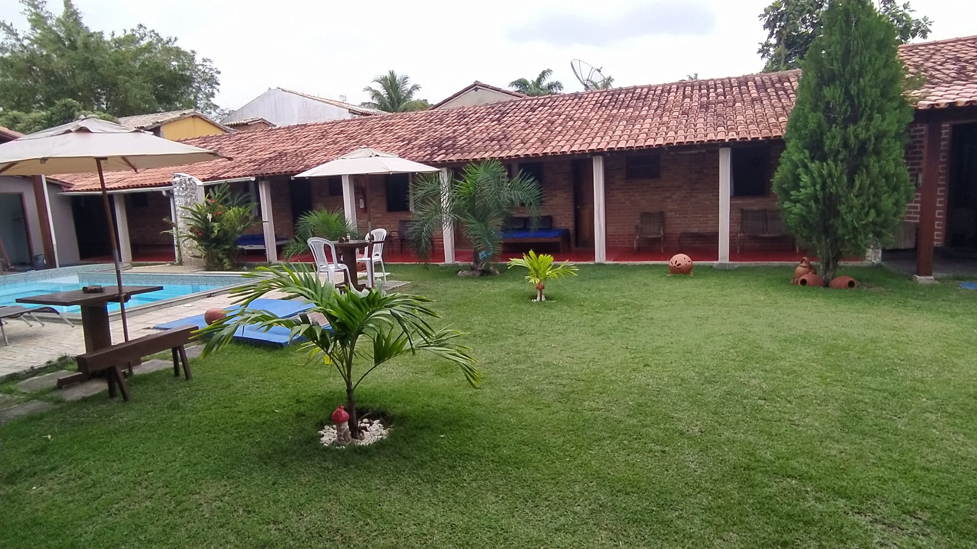 Un patio trasero con piscina, zona de barbacoa y terraza cubierta.