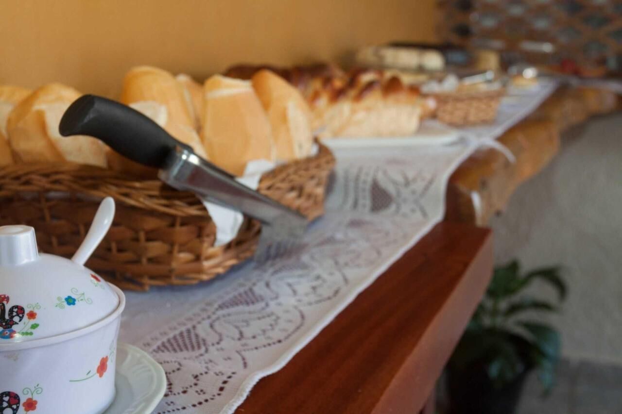 Un bufé de desayuno con pan, bollería y un cuchillo sobre una mesa con mantel de encaje.