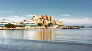 Une vue sur la côte, avec un bâtiment historique, des bateaux et un ciel dégagé.