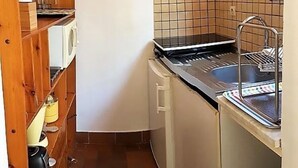 Une cuisine de taille réduite, équipée d’un four encastré, d’un évier et d’un four à micro-ondes.