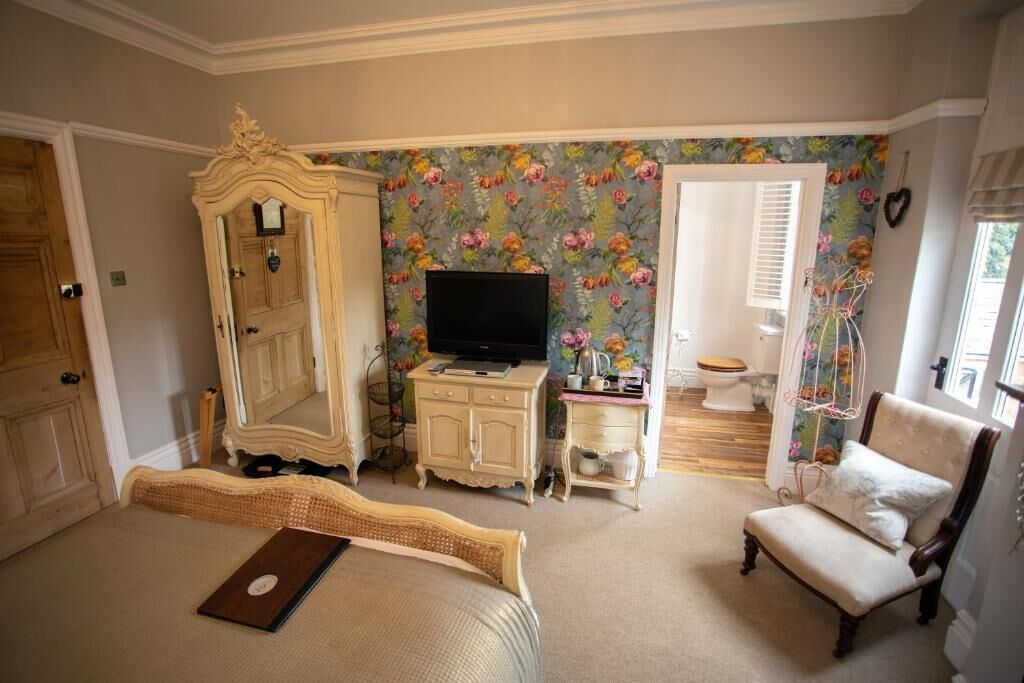 A bedroom with a bed, a television, a dresser, a chair, and a door.