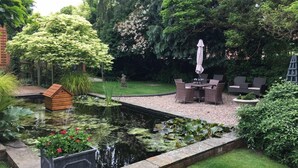 Un jardín con un estanque, un área de descanso y una estructura de madera.