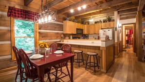 Ein Holzblockhaus-Interieur mit Essbereich, Küche und Bar.