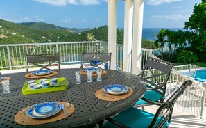 A dining table set with plates, glasses, and cutlery, overlooking a pool and a mountainous landscape. - Southern Breeze: Expansive Ocean Views! Amazing Sunrises! (St. John)