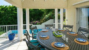 Un espacio de comedor al aire libre cubierto, con una piscina al fondo.