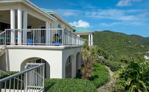 A building with a balcony, arched windows, and a pathway leading to a mountainous landscape. - Southern Breeze: Expansive Ocean Views! Amazing Sunrises! (St. John)