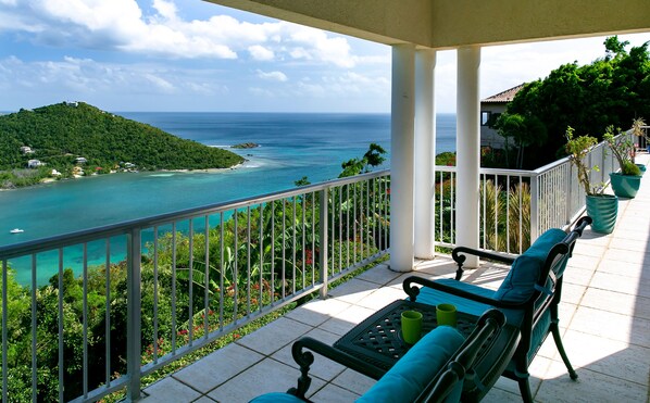 A balcony with a view of a coastal landscape, including a small island and the sea.