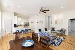 Un vaste espace de vie comprenant une table à manger, des canapés et un ventilateur de plafond.