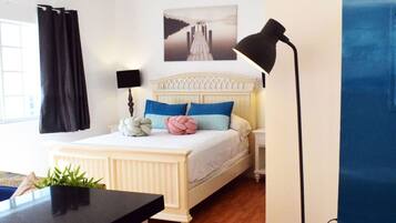 Un dormitorio con una cama, una mesita de noche, una lámpara, una ventana con cortinas y un cuadro colgado en la pared.