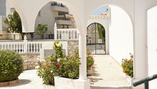 Un edificio blanco con arcos y una entrada con portón.