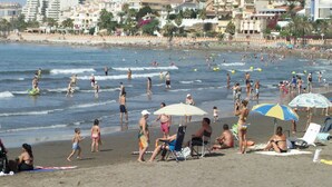 Una playa concurrida donde la gente se toma el sol y nada.