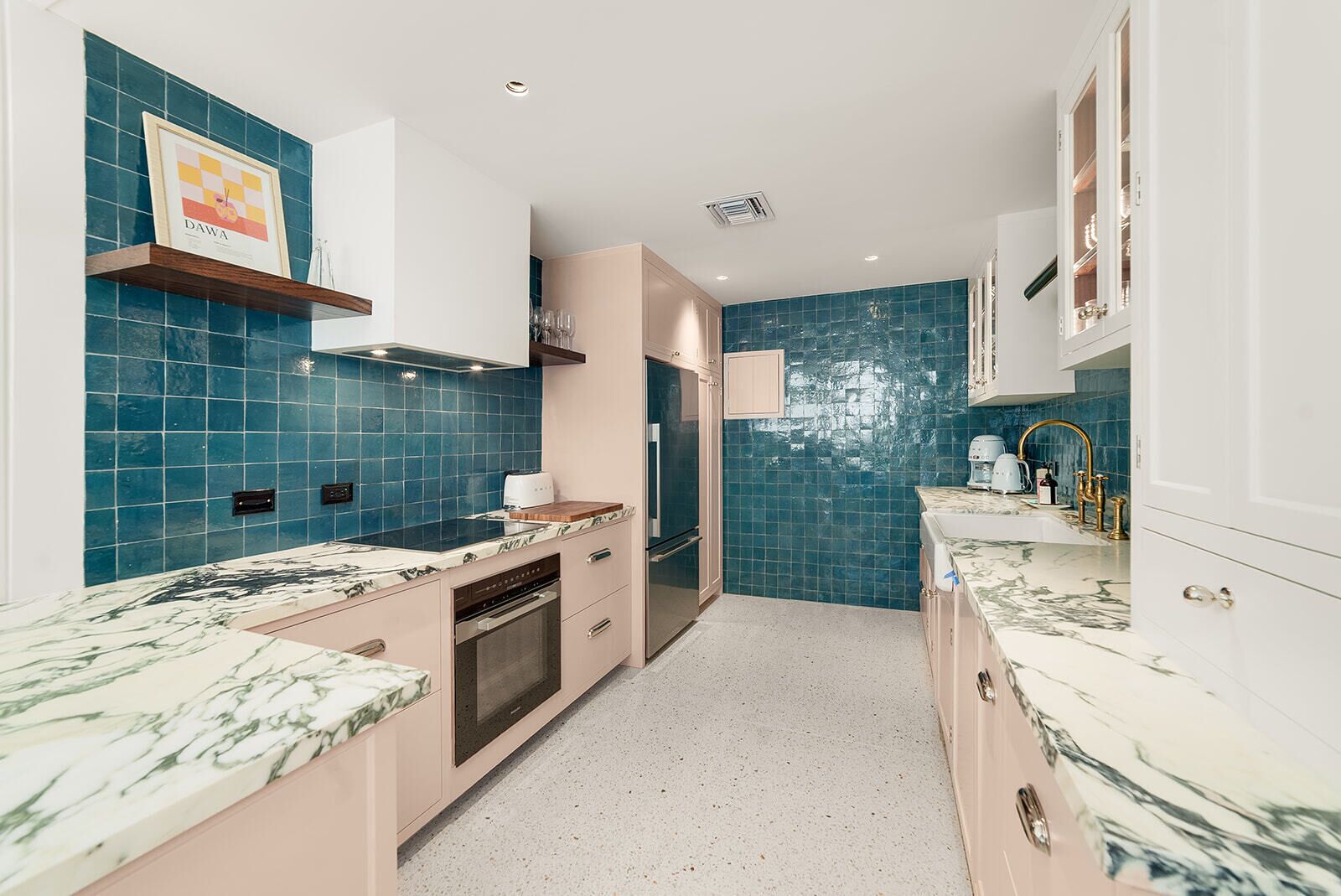 Una cocina moderna con azulejos azules, encimeras de mármol y electrodomésticos de acero inoxidable.