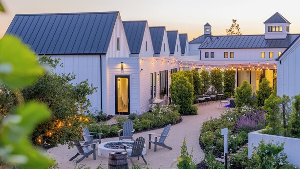 A courtyard with outdoor seating, a fire pit, and string lights. - The New Inn (Temecula)
