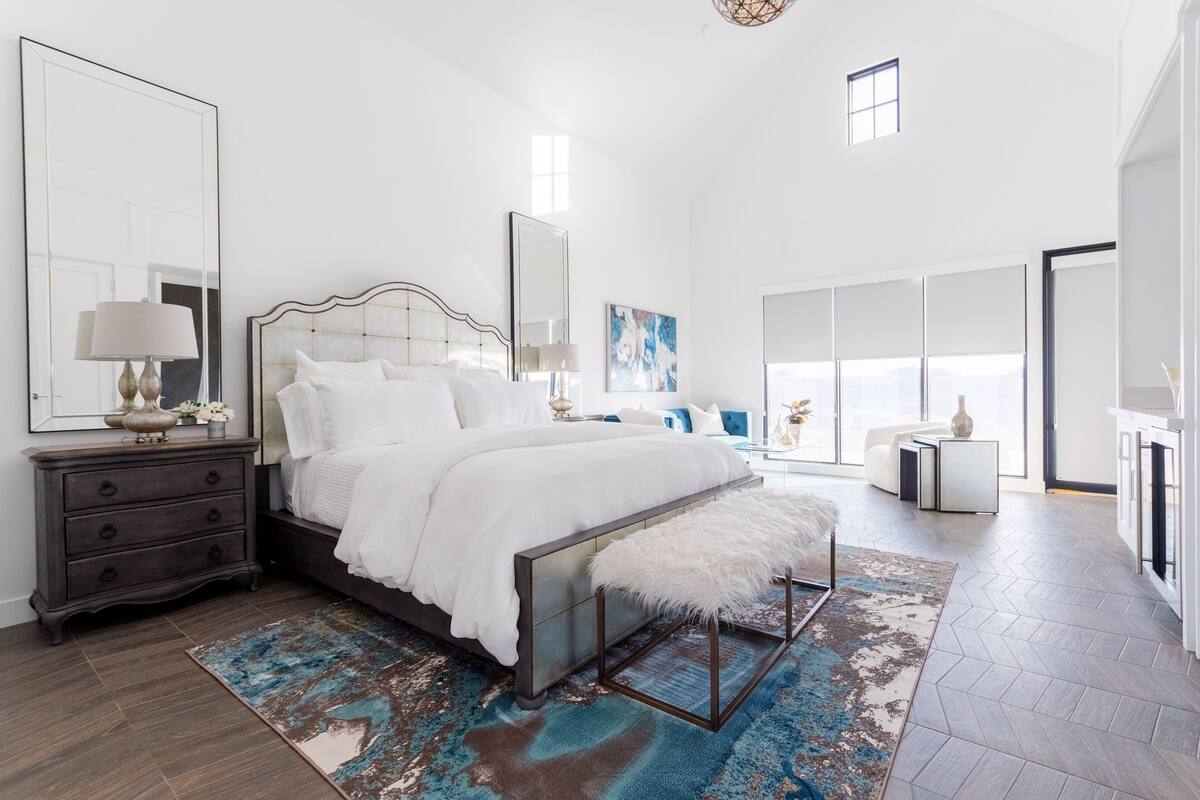 A spacious bedroom with a large bed, a dresser, and a mirror.
