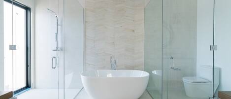 A modern bathroom with a freestanding bathtub, a glass-enclosed shower, and a toilet.