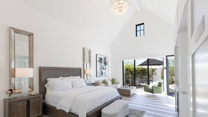 A spacious bedroom with a large bed, a nightstand, a mirror, and a view of the outdoor patio. - The New Inn (Temecula)
