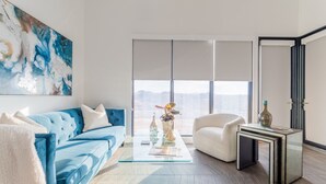A modern living room with a blue sofa, a glass coffee table, and a white armchair. - The New Inn (Temecula)